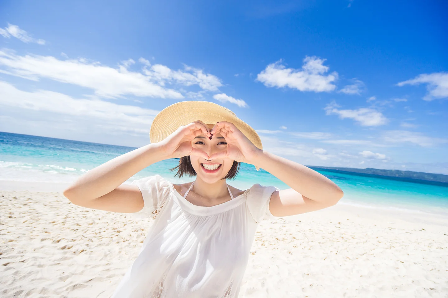 Lady making love heart with hands on the beach.jpg