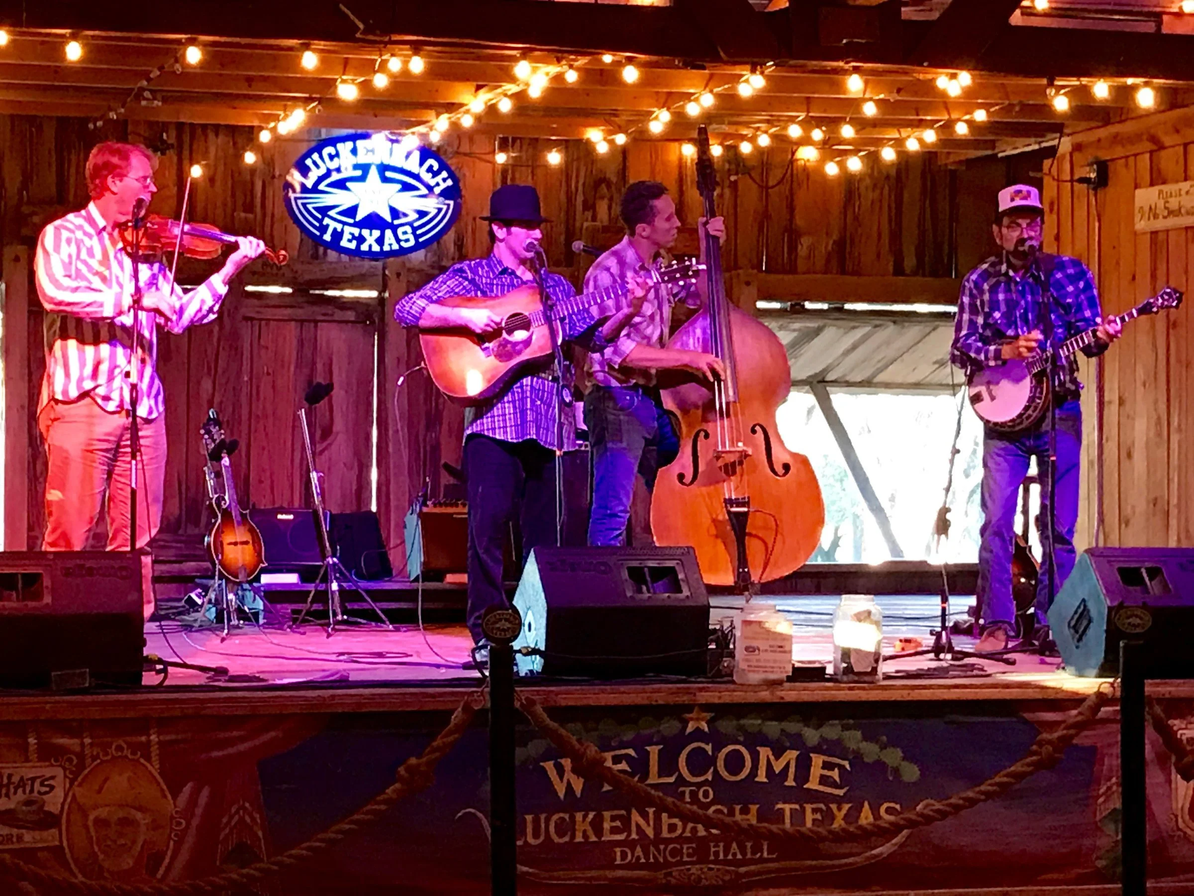Hot Pickin 57s performing at the Luckenbach Dance Hall under string lights and the neon Luckenbach Texas sign
