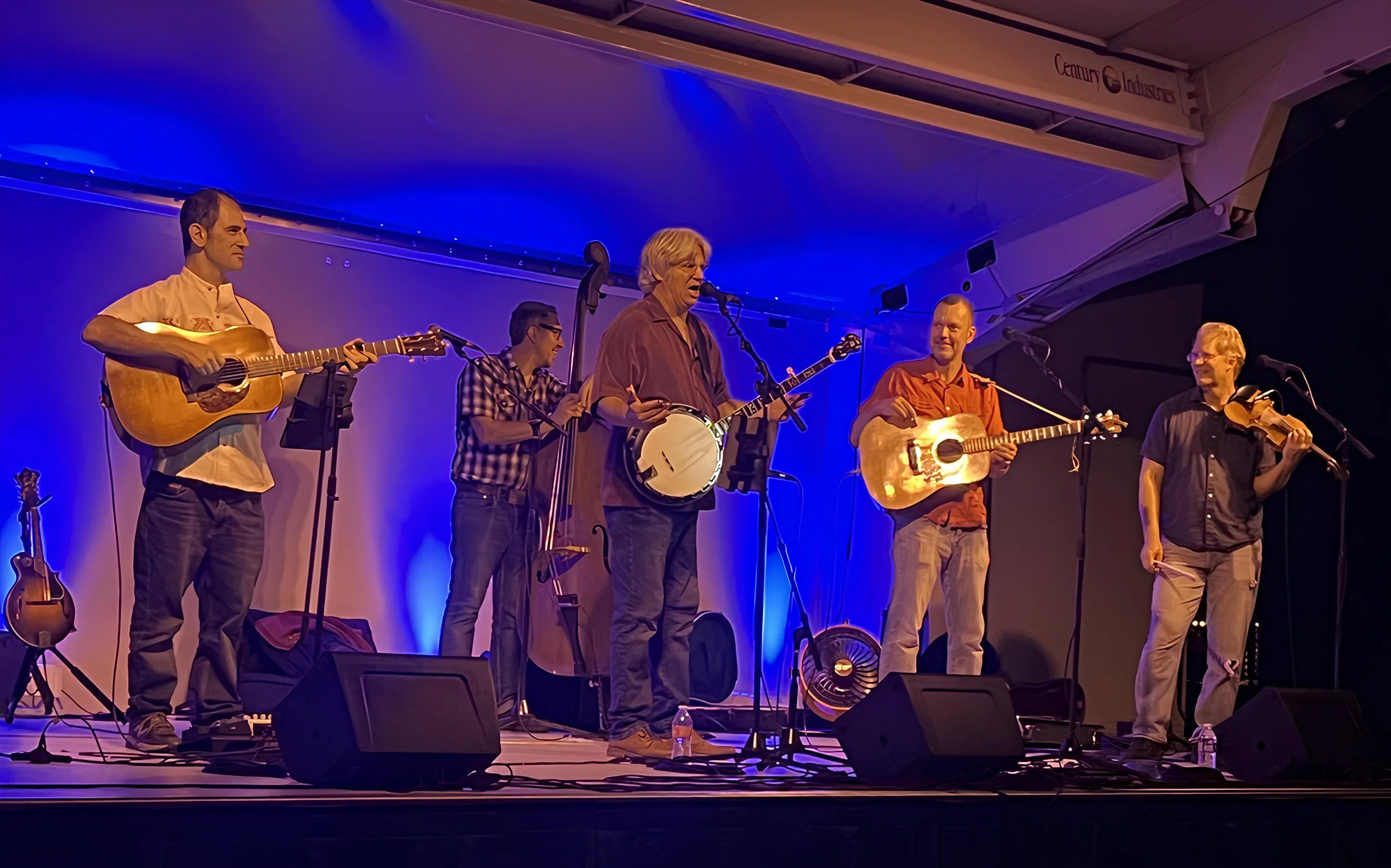 Hot Pickin 57s performing as a five-piece with guitar, bass, banjo, second guitar and fiddle under blue stage lights