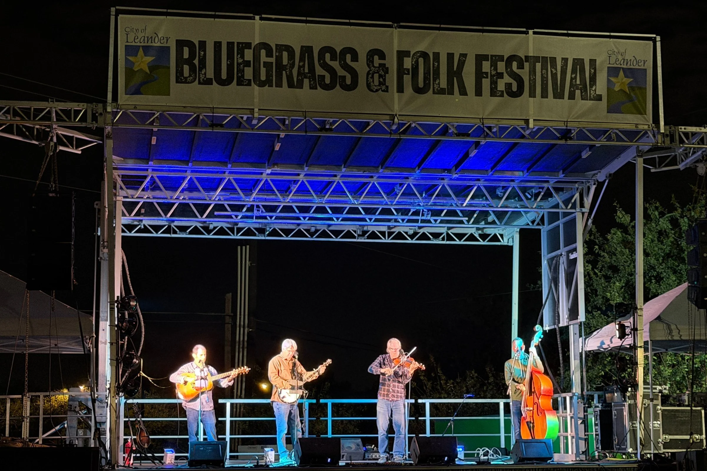 Hot Pickin 57s performing at night on the Leander Bluegrass & Folk Festival stage under the festival banner