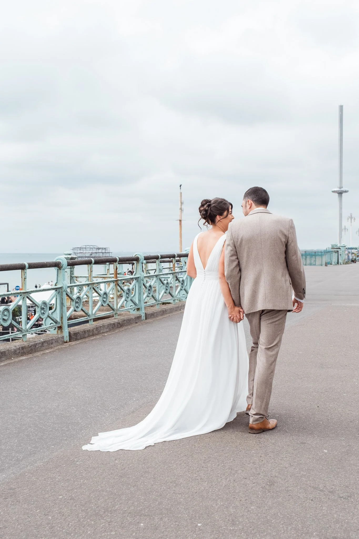Bride and  Groom walking Brighton Promenade. i360 and West Pier behind
