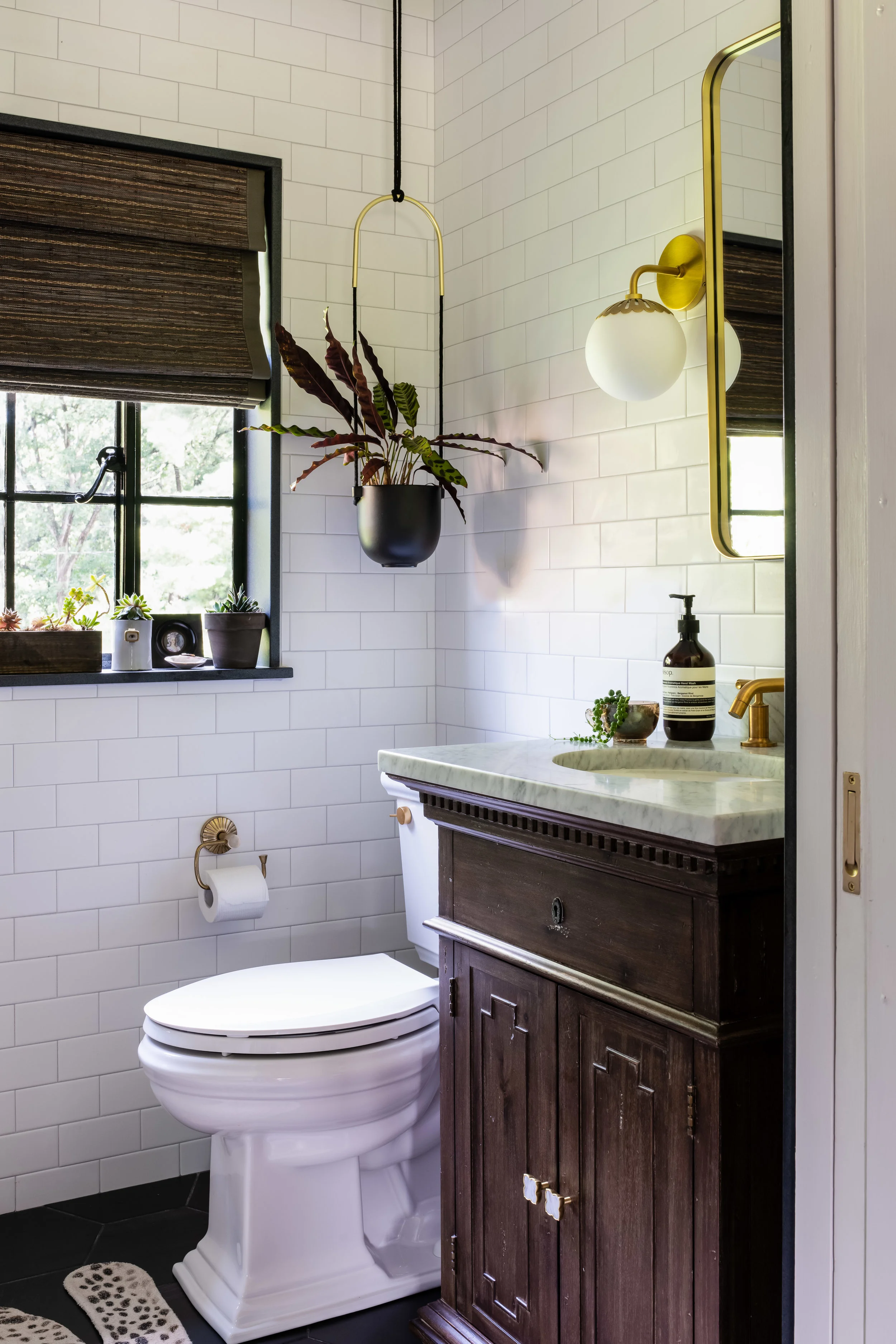 Tile: Best Tile ; Vanity & Medicine Cabinet, Restoration Hardware ; Kohler Toilet & Faucet; Shades of Light Sconce; Umbra Hanging Plant Holder ; Bath Matt, Urban Outfitters ; Smith and Noble Blind . Design: Noelani Zervas // Photo: Jessica Delaney Photography LaniZervas_Tudor_MasterBathroom_JessicaDelaney_BijOU