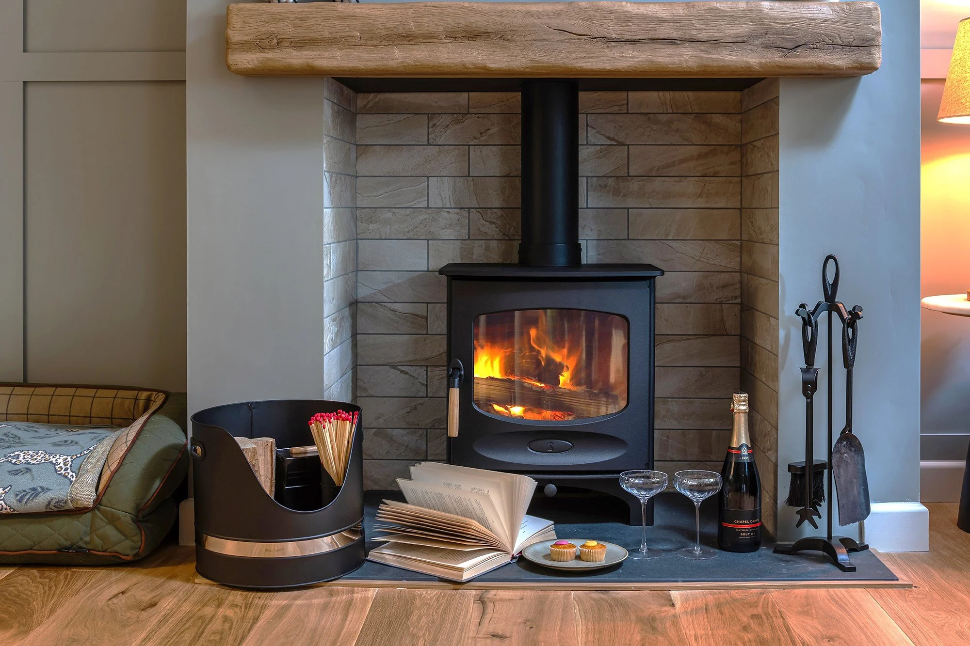 A cozy living room at New-Stables Cottage in Stow-on-the-Wold, featuring a warm, lit wood-burning stove and a relaxing atmosphere