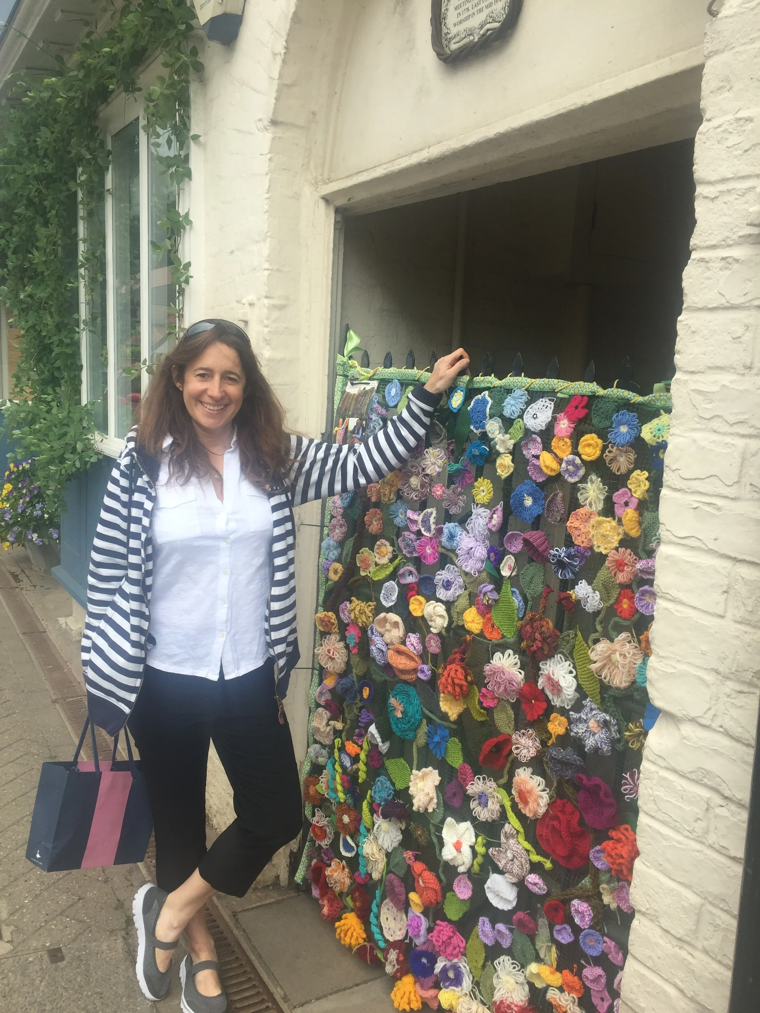 Amanda standing next to a colorful, handmade knitted display in a doorway during the Shipston Wool Fair