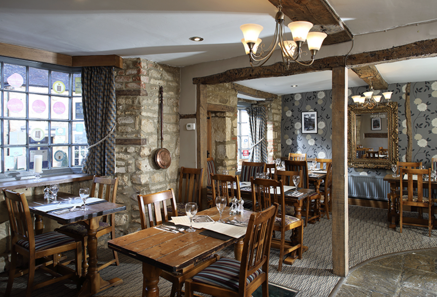 The warm and inviting interior of the 14th-century Eight Bells Inn in Chipping Campden, featuring cosy tables and rustic charm