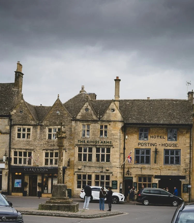 A view of the historic market square in Stow-on-the-Wold, featuring traditional stone buildings including The Kings Arms and The Porch House