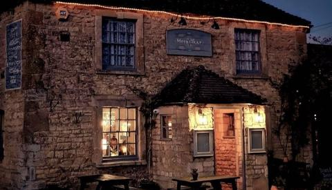 Exterior evening view of The Mousetrap Inn in Bourton-on-the-Water, showing the lit historic stone building facade and front entrance porch