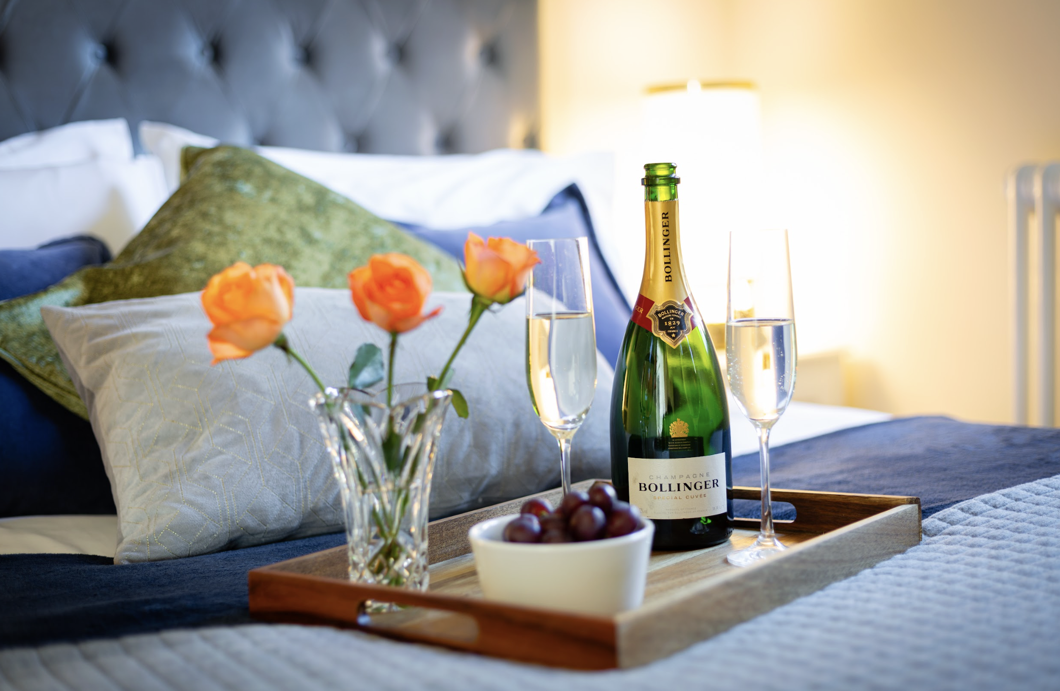 A romantic setup at Honey Pot in Chiping Campden, featuring a bed with champagne and fresh flowers on a tray