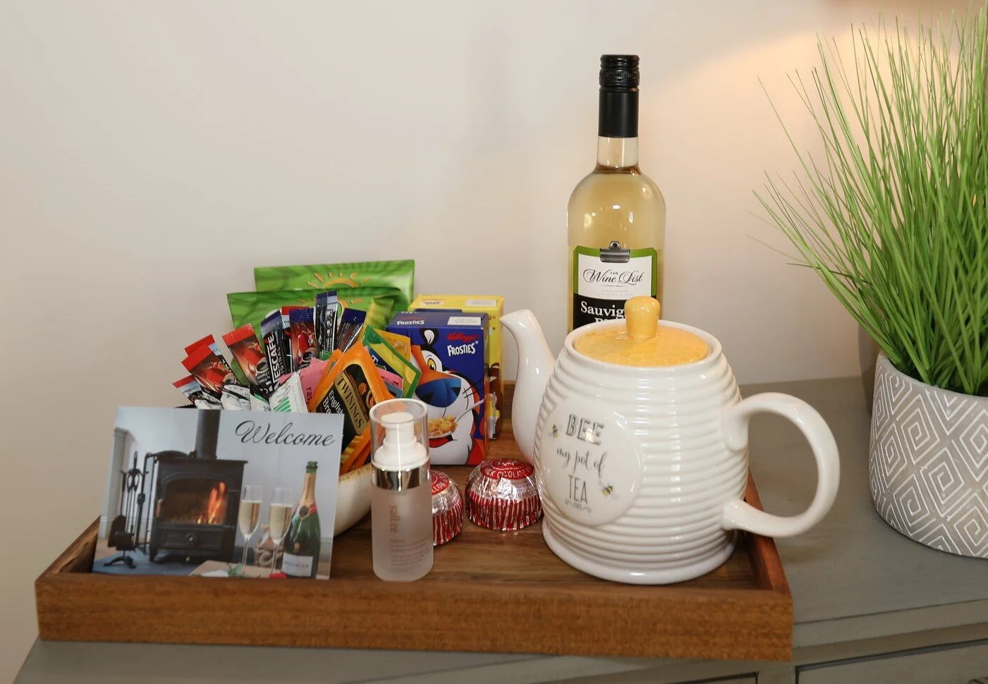 A curated welcome tray at honeypot cottage, featuring a selection of high-quality local treats, wine, and a tea set to greet guests upon arrival
