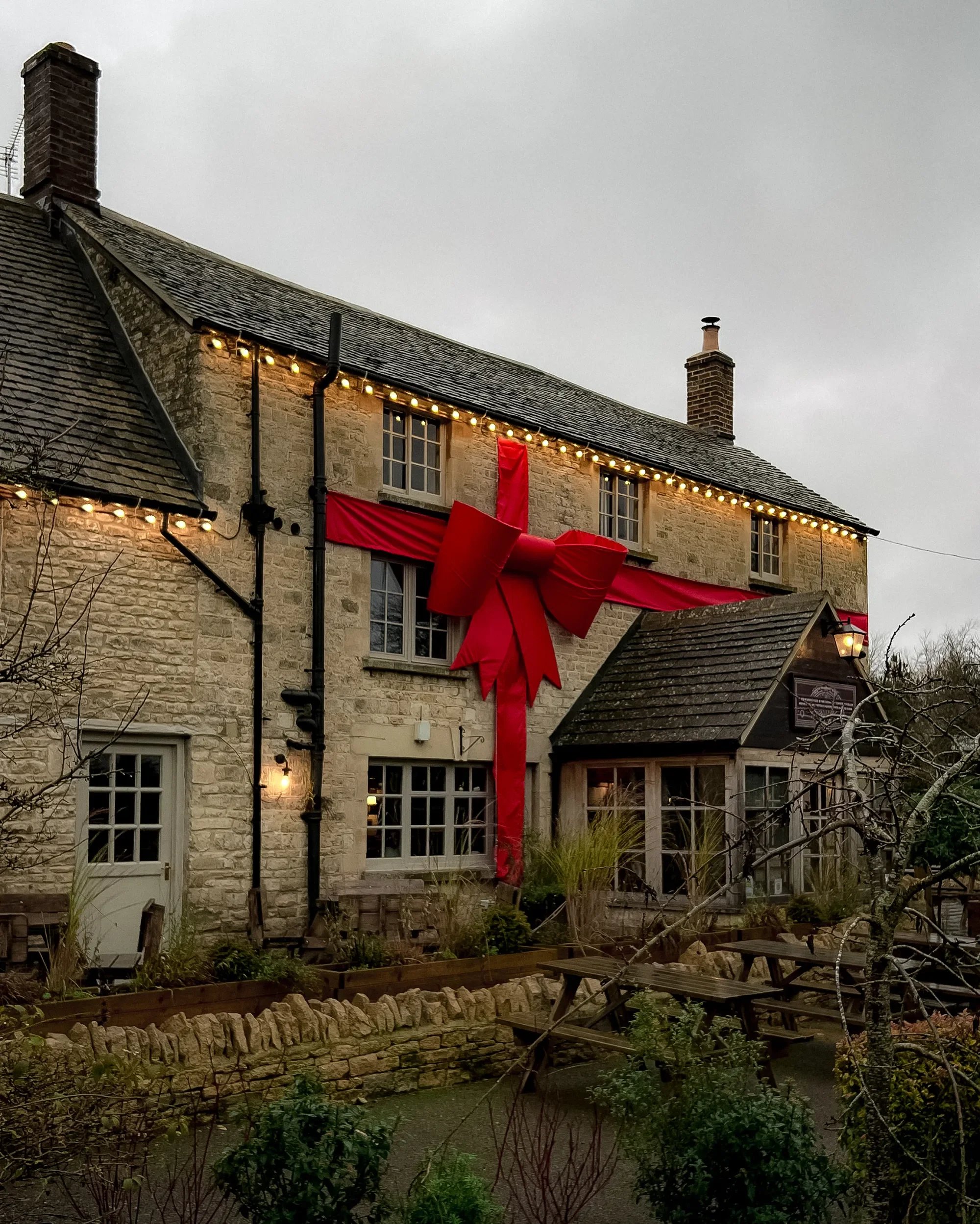 A stone building, The Killingworth Castle, decorated with a large red ribbon bow and festive lights for the holiday season