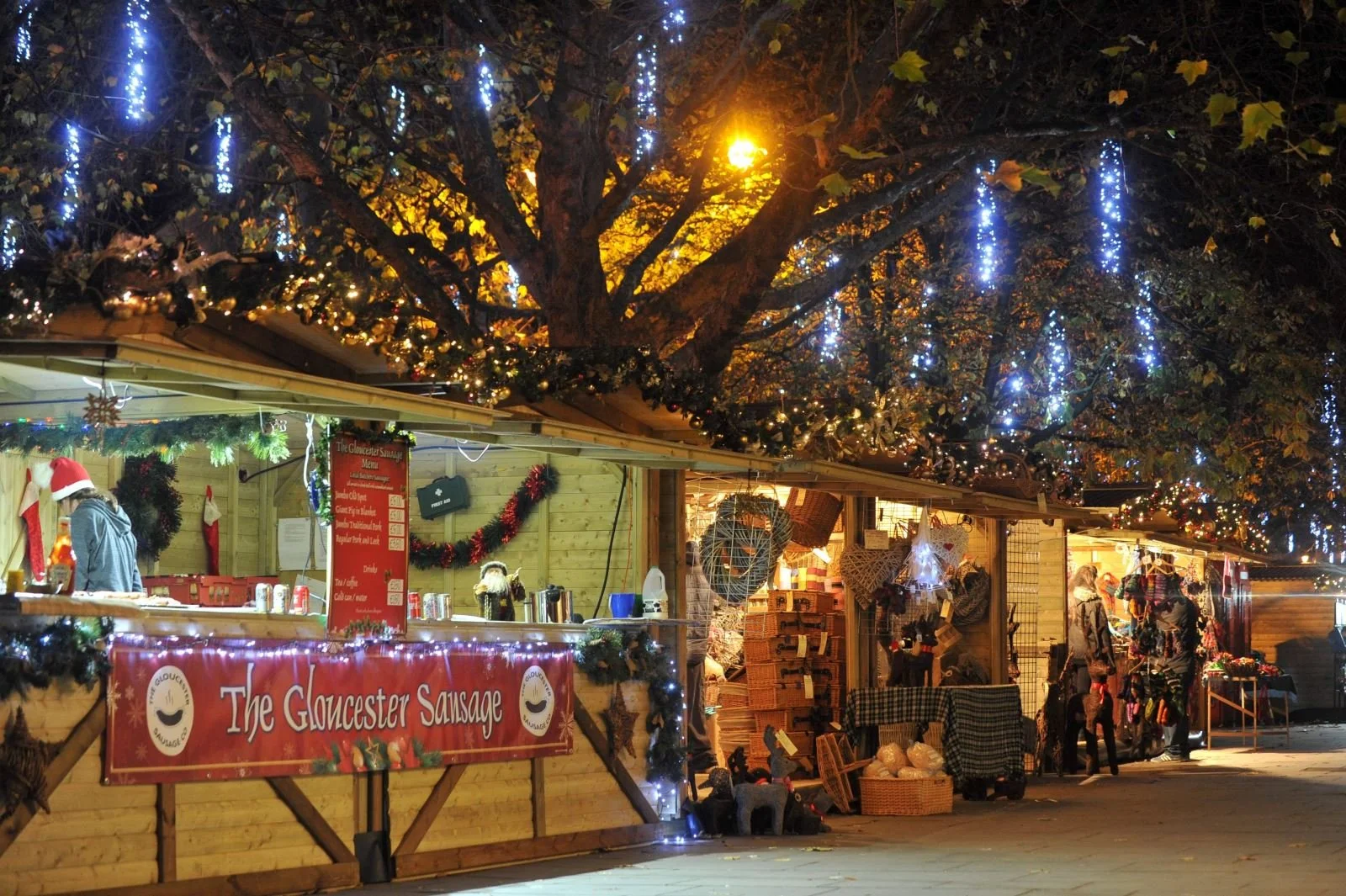 A cosy, well-lit Christmas market stall in Cheltenham decorated with festive lights and holiday displays