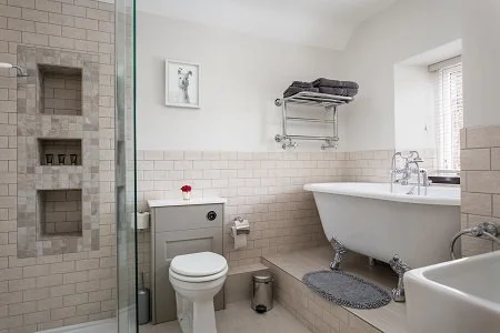 A bright and clean bathroom at Little Gem Cottage, featuring a classic roll-top bathtub and tiled walls