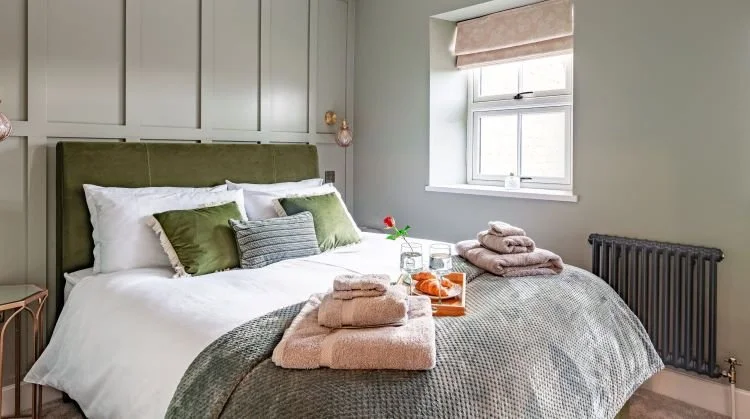 A master bedroom in Hideaway Cottage featuring elegant wood panelling, a king-size bed with soft linens, and a bright, inviting atmosphere