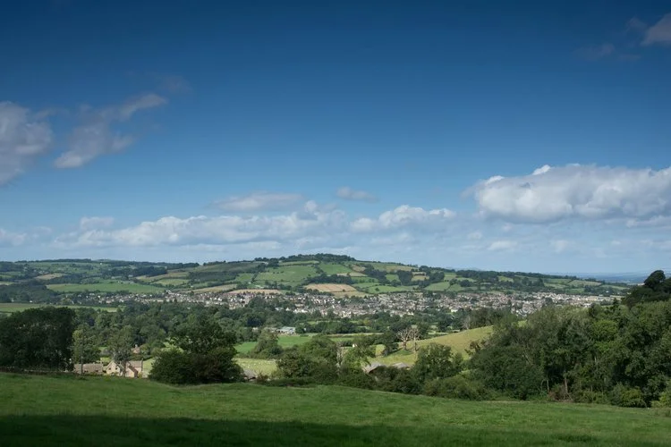 A scenic panoramic view of the rolling Cotswold countryside from Belas Knap, a Neolithic long barrow