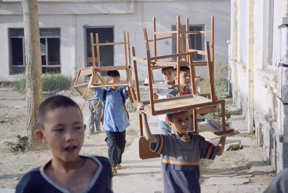  Orphans carry their chairs to prepare an open classroom in Kabul orphanage, Afghanistan, April, 15, 2003. AFP PHOTO/MASSOUD Hossaini     