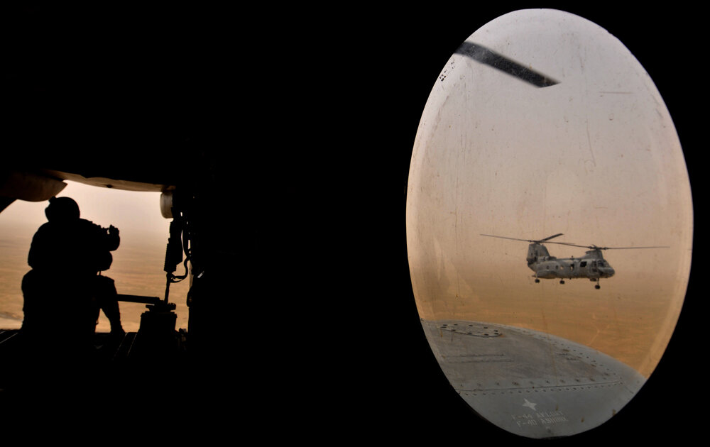  A US soldier (L) sits alert in a Marine Chinook helicopter while flying over camp Bastion in Helmand province, southwest of capital Kabul on May 3, 2008. About 3000 British troops along with Danish, Estonian, Czech and American troops are based in C