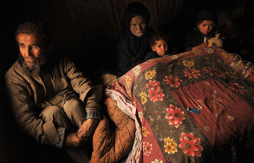  An Afghan man, Sakhi 65 (L) sits on the ground with his family at his house in Kabul on February 16, 2008. More than 500 homes, mostly traditional mud brick houses, have been destroyed and tens of thousands damaged by the heaviest snowfalls in 30 ye