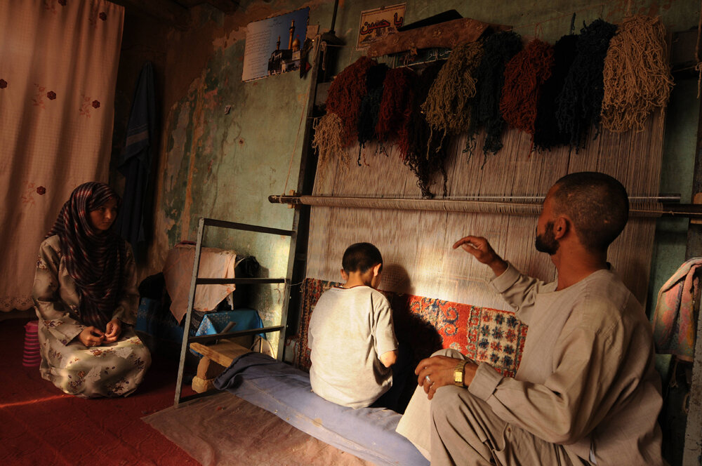  An Afghan man, Mohammad, 37, first right talks to his son Asif (C) while they weave a carpet on a loom at their home in Kabul on June 10, 2008. For centuries, Afghanistan was recognized as a global leader in carpet production. But after the Taliban 