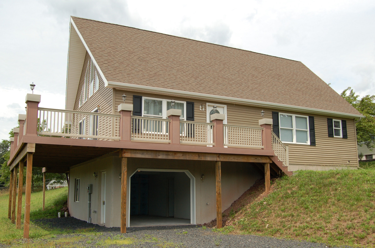 Exterior View from Front showing Wrap Around Composite Deck with Planter boxes on each Newel Post and Drive-in 1-car garage.