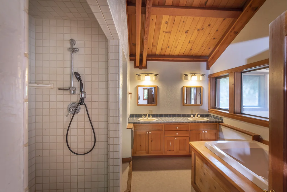Large bathroom, tiled shower, tub, wood finishes.