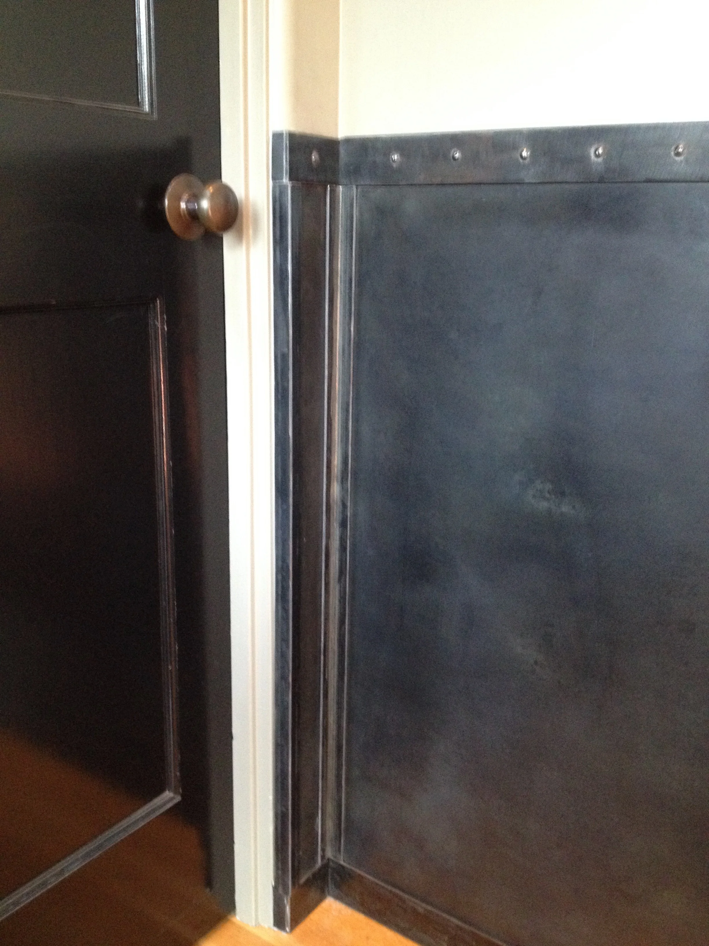 Steel Wainscoting Custom steel wainscoting for a client in Larkspur, California. Designed with an elegant industrial style, this project jazzed up a previously boring entryway while protecting the walls from nicks and dents caused by daily life with children. Details include handmade faux rivets, black patina, and a hand-rubbed wax finish.