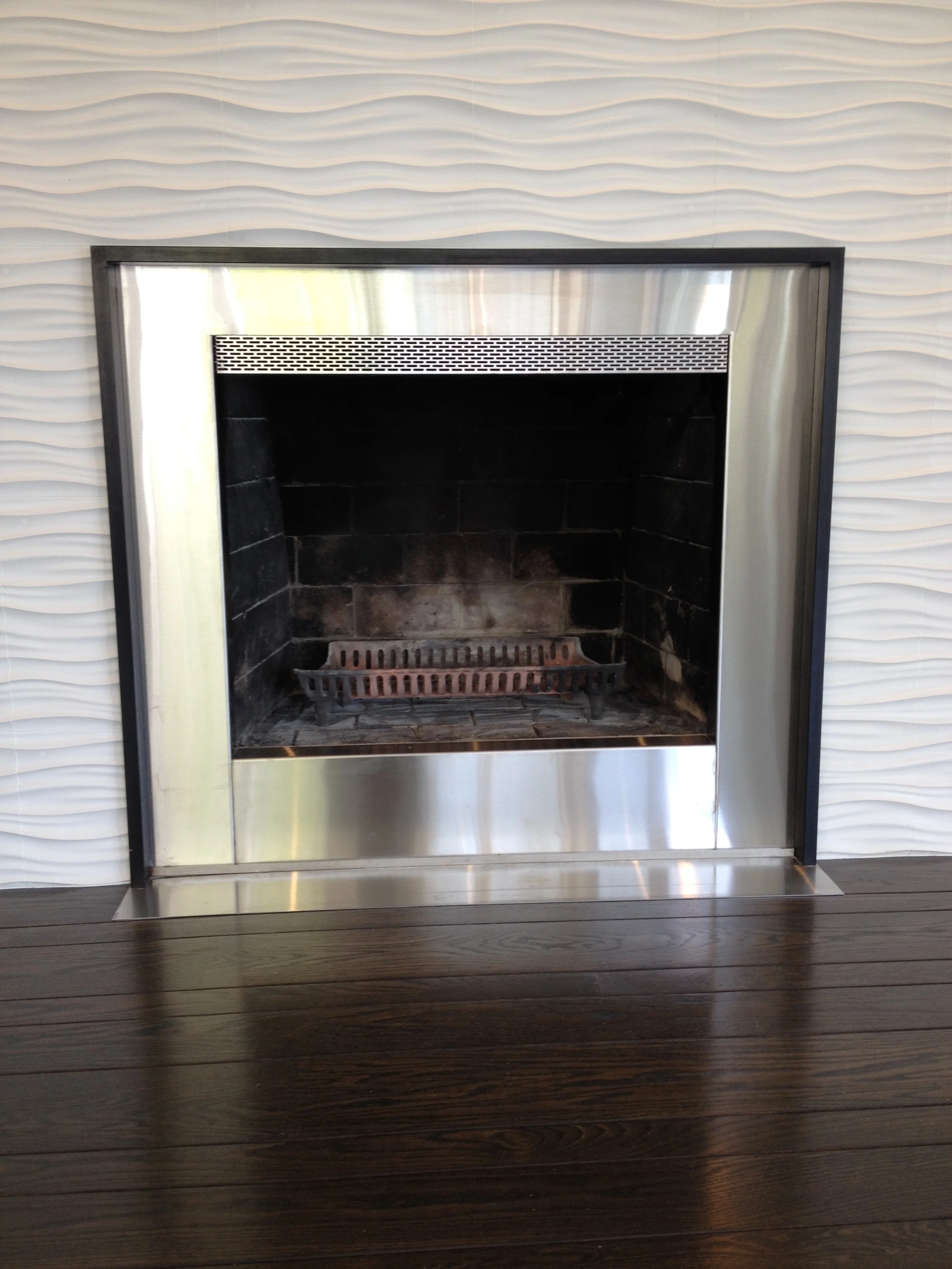 Stainless Steel Fireplace Surround This fireplace surround was a client's own design. Made from brushed stainless steel, it has a powdercoated tubular steel frame, and stainless steel hearth. The finishing touch is the custom-perforated stainless detail strip. Fire light will shine through the holes!
