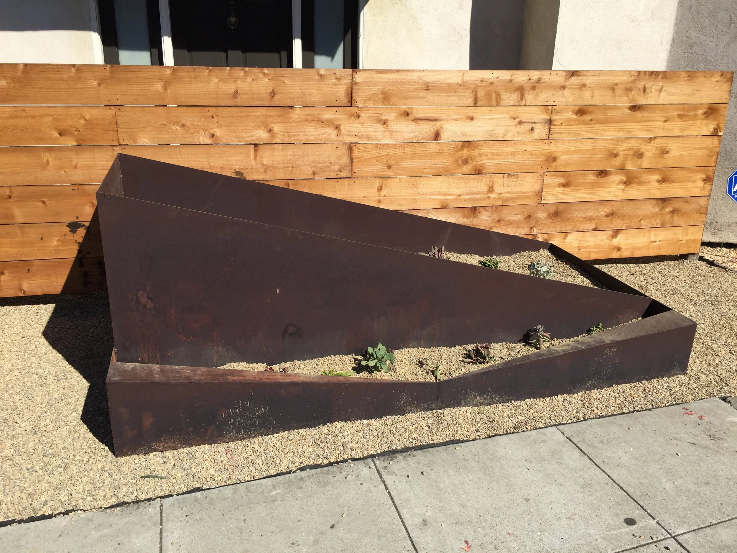 Corten Angled Planter Box This uniquely-styled angular planter box provides a haven for the succulents growing inside.