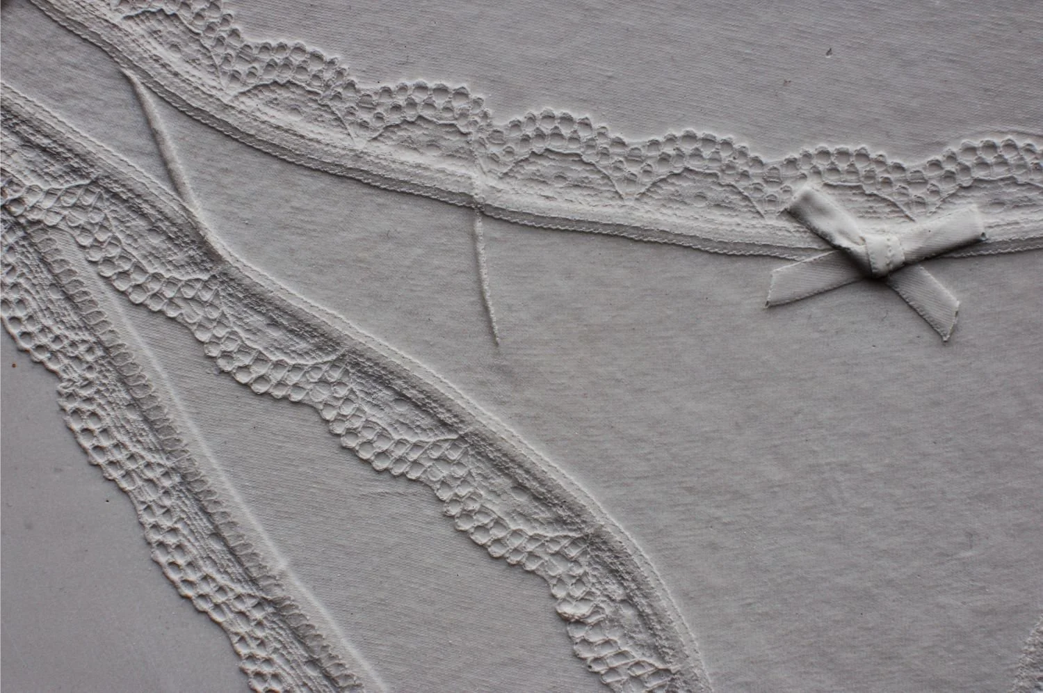 Detail of Brief Histories, a pale Jesmonite relief preserving delicate impressions of leaves and stems.