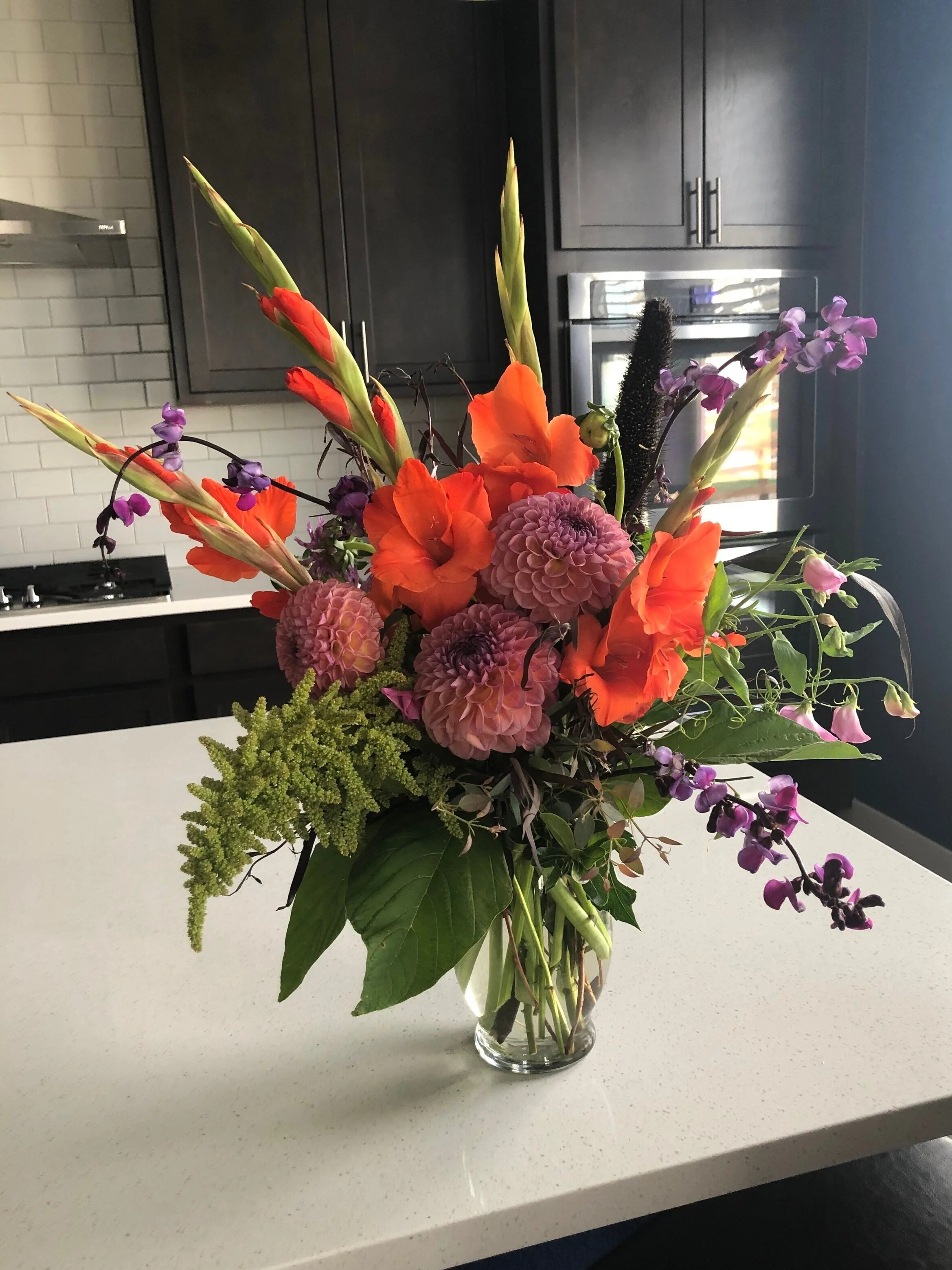 Elegant summertime arrangement with locally sourced blooms in orange and purple by Snowdrops and Sage