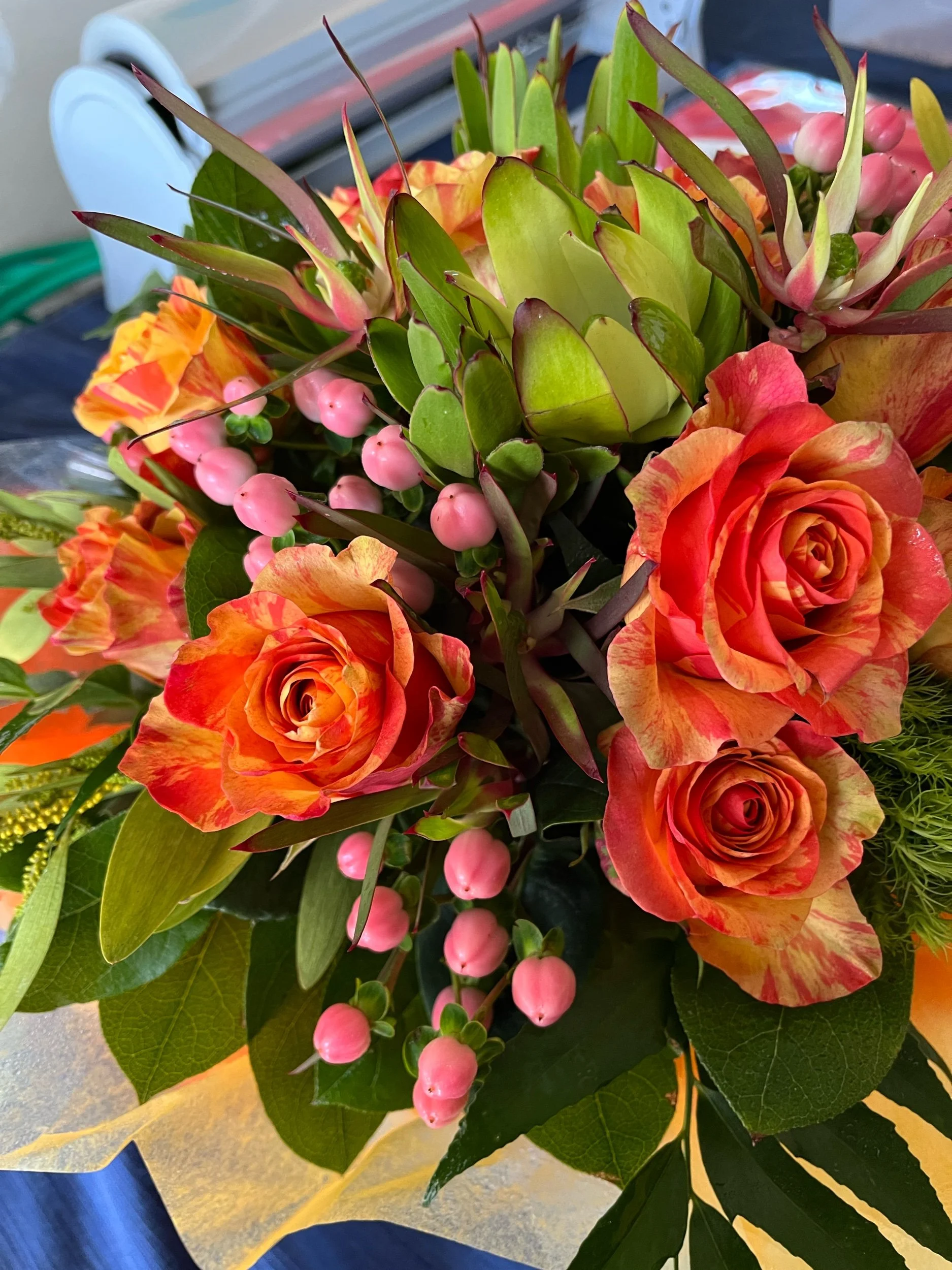 Bright floral arrangement with orange and pink flowers and lush greenery by Snowdrops & Sage