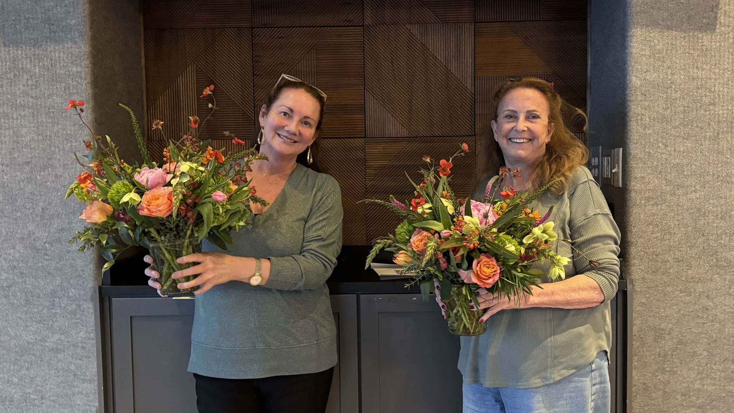 Two women displaying beautiful flower arrangements