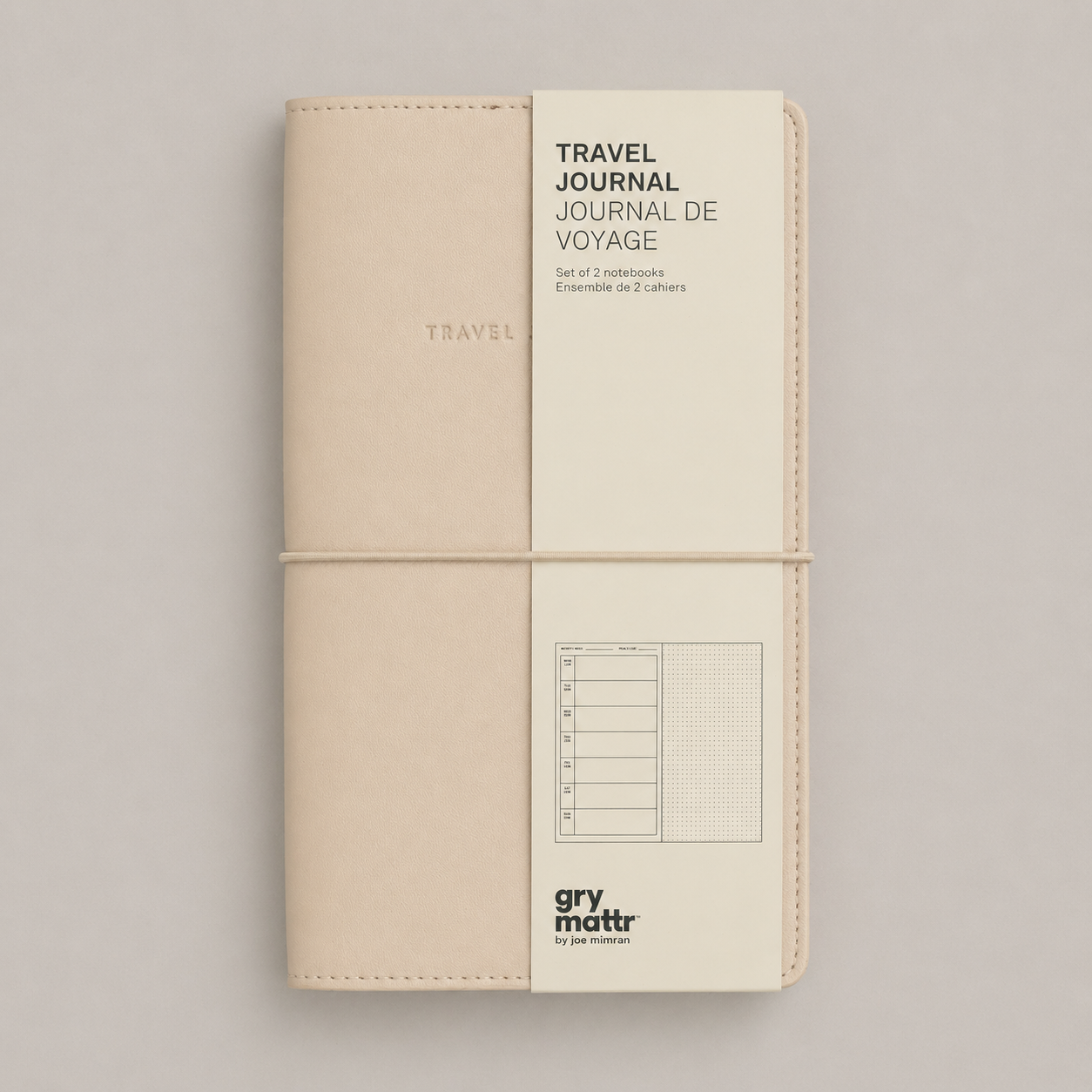 A closed, beige travel journal with a white paper band around it that reads "Travel Journal" in English and French, with extra details about the content and brand logo at the bottom.