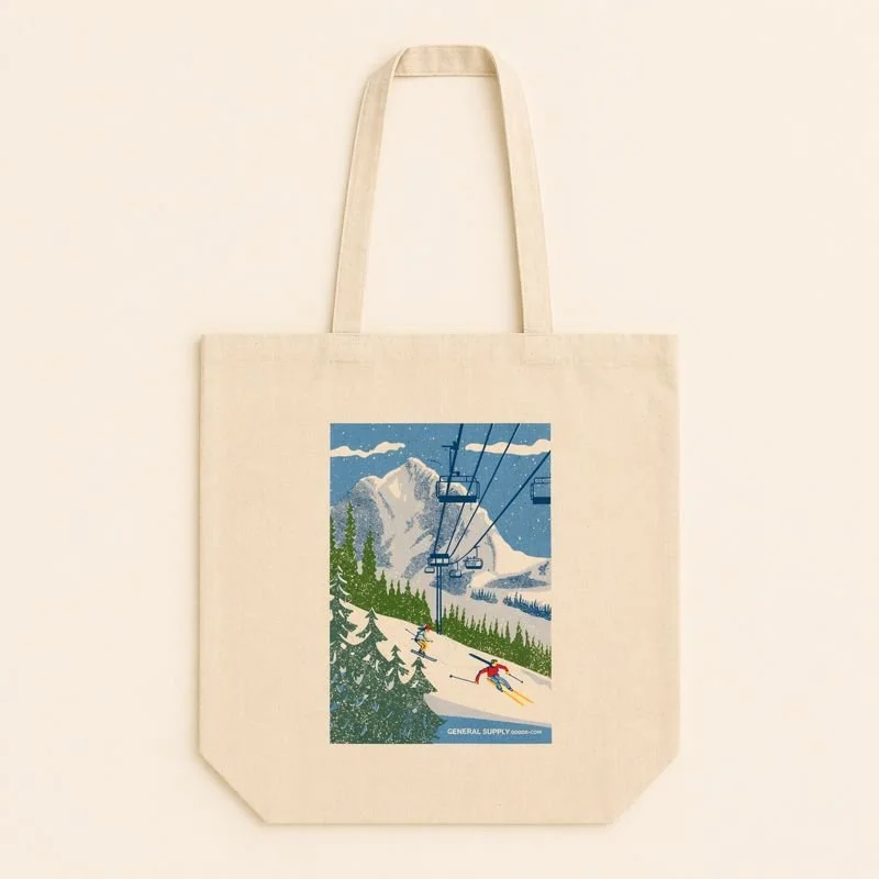 Canvas tote bag with a graphic of skiers on a snowy mountain with a ski lift and trees.