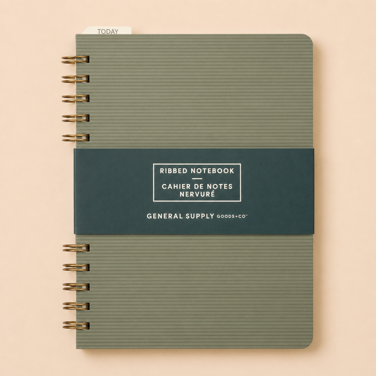 A ribbed hardcover notebook with a dark blue band around the middle that has white text reading 'RIBBED NOTEBOOK,' 'CAHIER DE NOTES,' 'NERVURÉ,' and 'GENERAL SUPPLY GOODS+CO,' on a beige background.