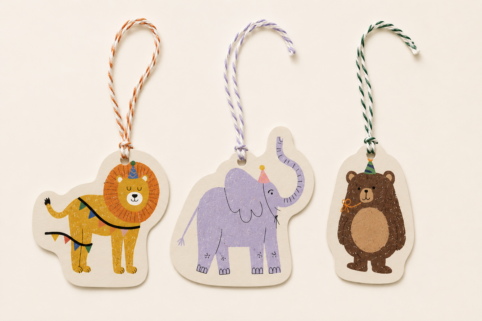 Three animal-themed holiday gift tags with strings, featuring a lion, an elephant, and a bear, all wearing party hats.