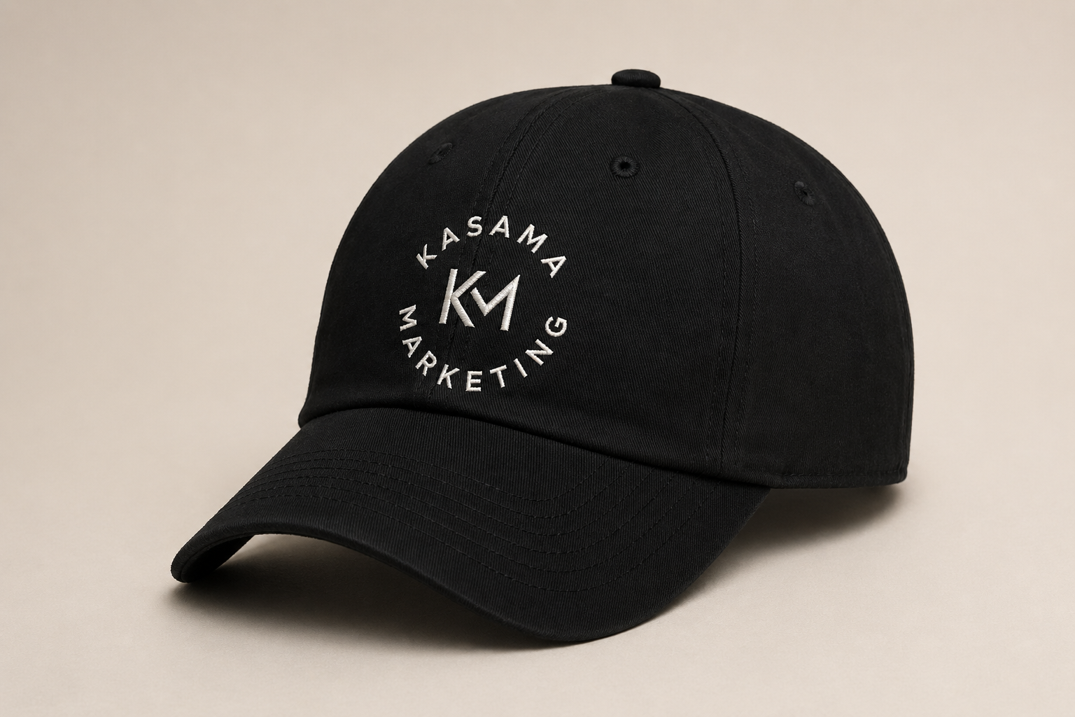 Black baseball cap with white embroidered logo reading 'Kasama Marketing' and initials 'KM'.