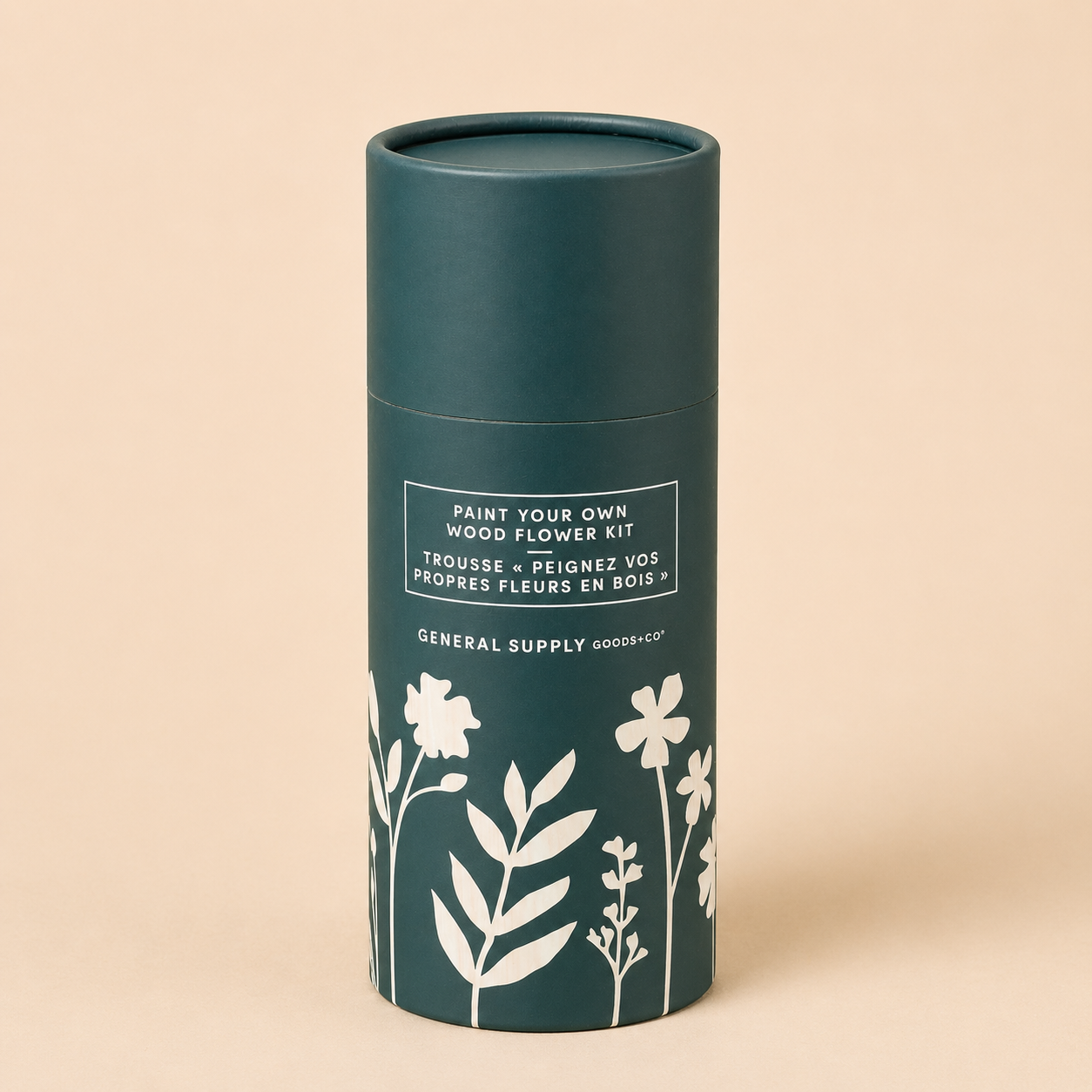 A cylindrical container with a dark teal color and floral designs containing a "Paint Your Own Wood Flower Kit" from General Supply Goods+Co.