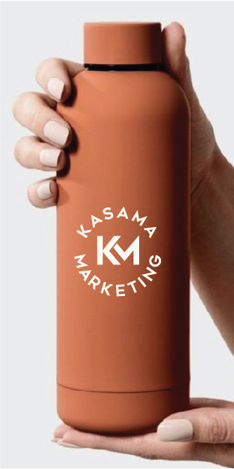 Hand holding a brown tumbler with Kasama Marketing logo printed in white