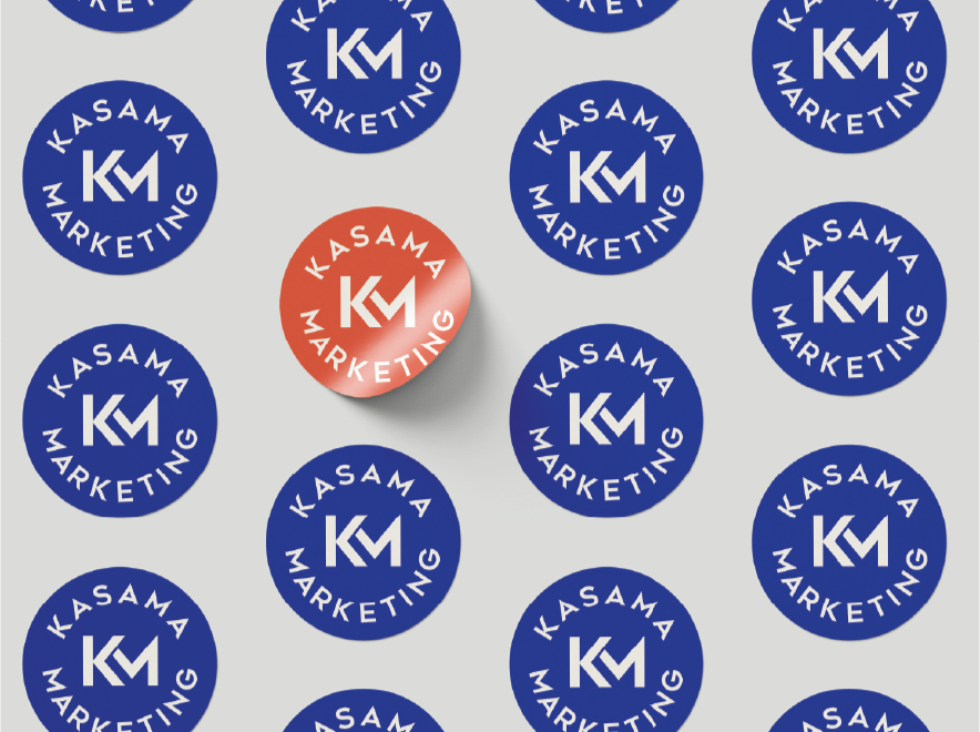 Pattern of round stickers with blue backgrounds and white text that says 'KASAMA MARKETING', with a single sticker in the center that is red with white text that says 'KASAMA MARKETING' casting a shadow.