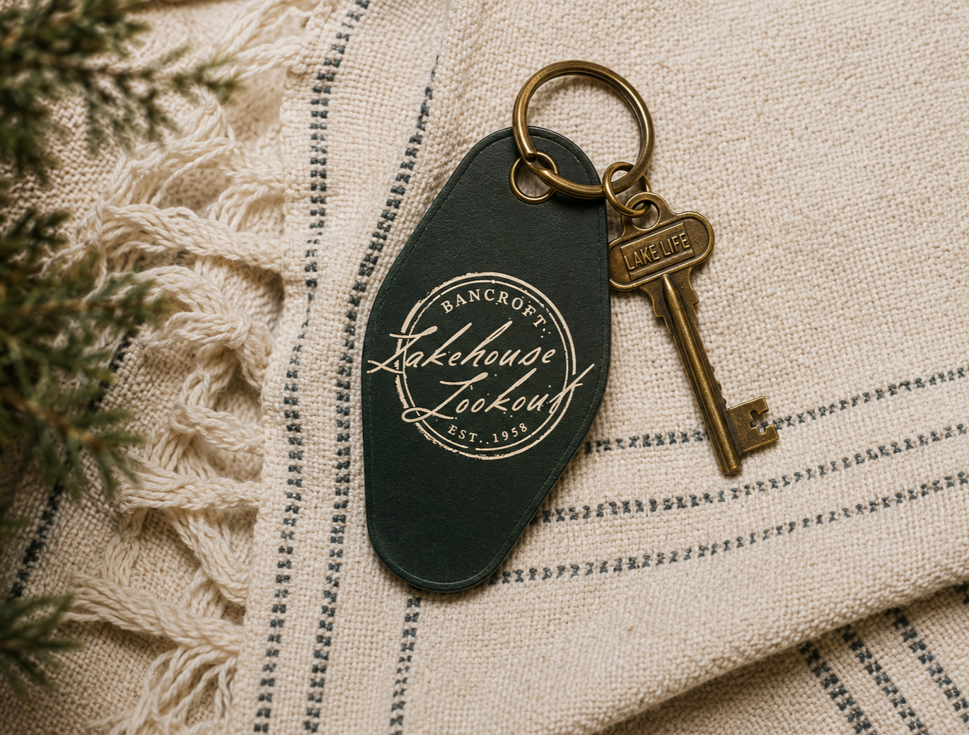 A set of keys with a keychain reading 'Lake House Lookout' on a cream and blue woven blanket.