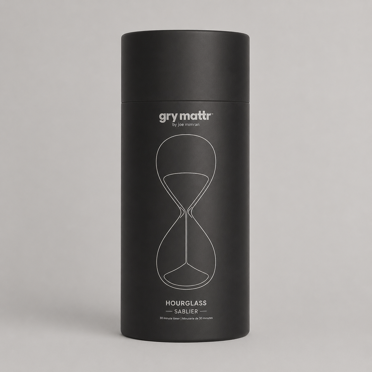 A black cylindrical container with a minimalist hourglass design and text, labeled "Grymatr by Joe Mimran, Hourglass, Sablier, 30 minute timer."