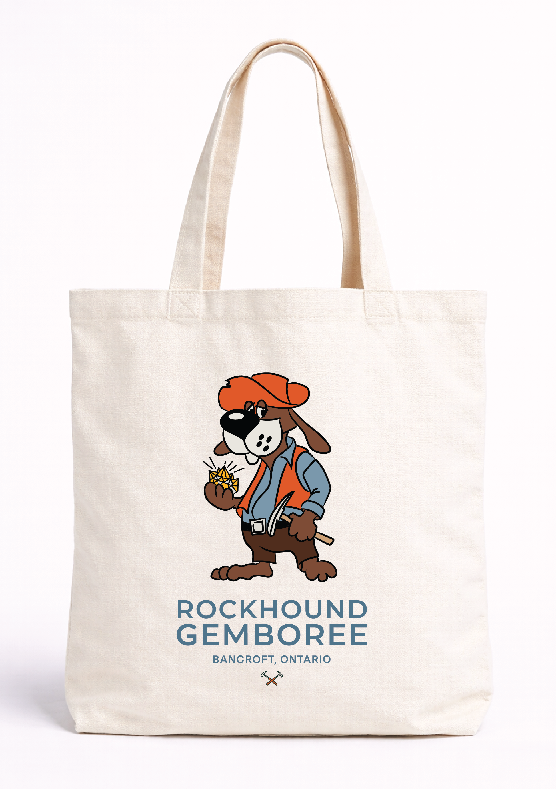 A white tote bag featuring a cartoon dog character dressed as a lumberjack, with text below indicating 'Rockhound Gemboree' in Bancroft, Ontario.
