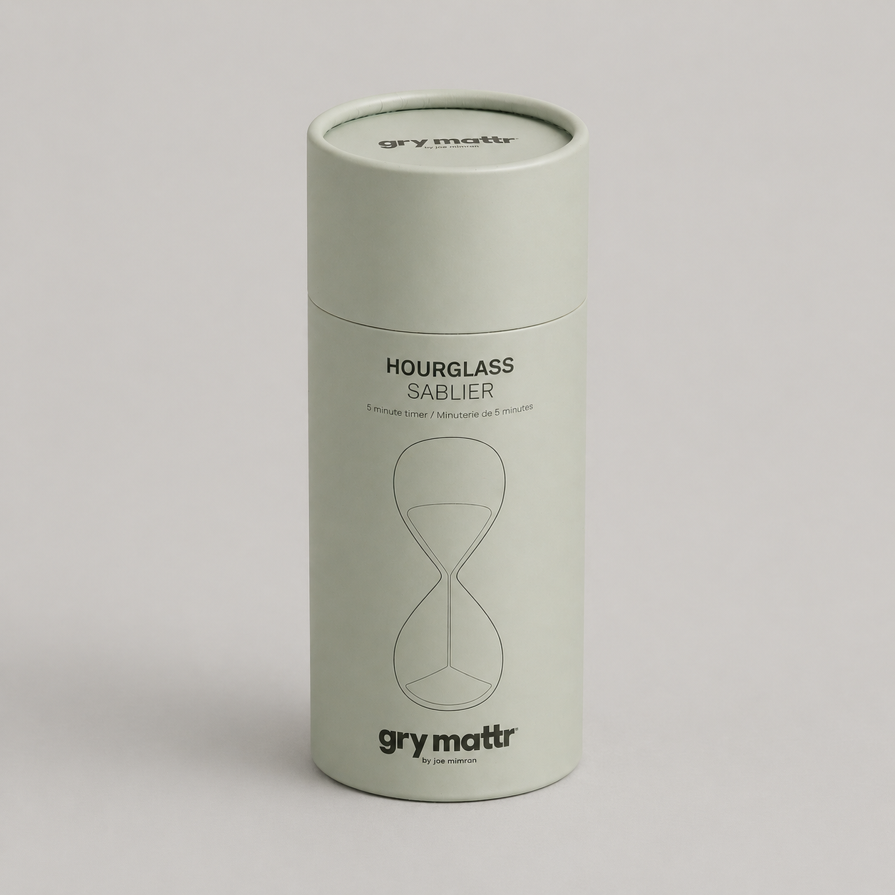 White cylindrical timer labeled "Hourglass Sablier," with a simple hourglass line drawing and the brand name "gry mattr" at the bottom.