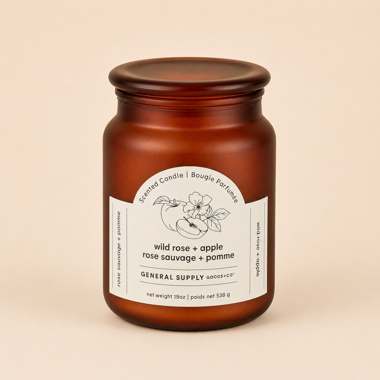 Amber glass jar candle with a white label featuring a line drawing of a rose and apple, labeled as wild rose and apple scented candle.