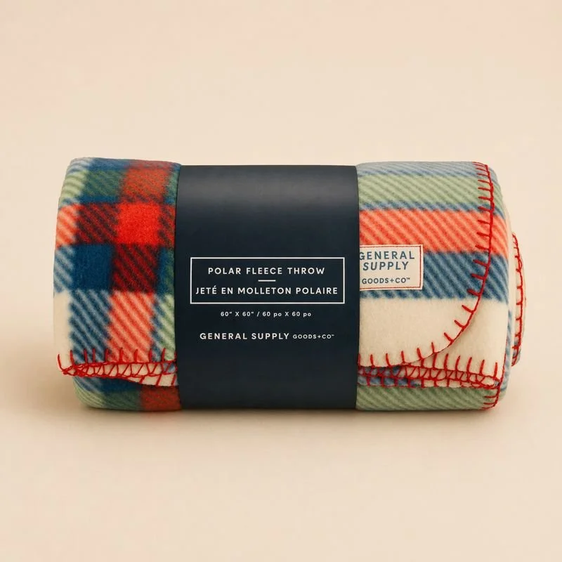 Rolled polar fleece throw blanket in plaid pattern with red stitching, labeled 'Polar Fleece Throw' from General Supply Goods.