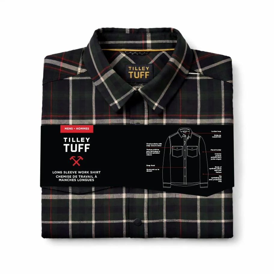 A folded Tilley Tuff long sleeve work shirt with a black, green, white, and red plaid pattern, wrapped with a black label band featuring white and red text and a line drawing of the shirt design.