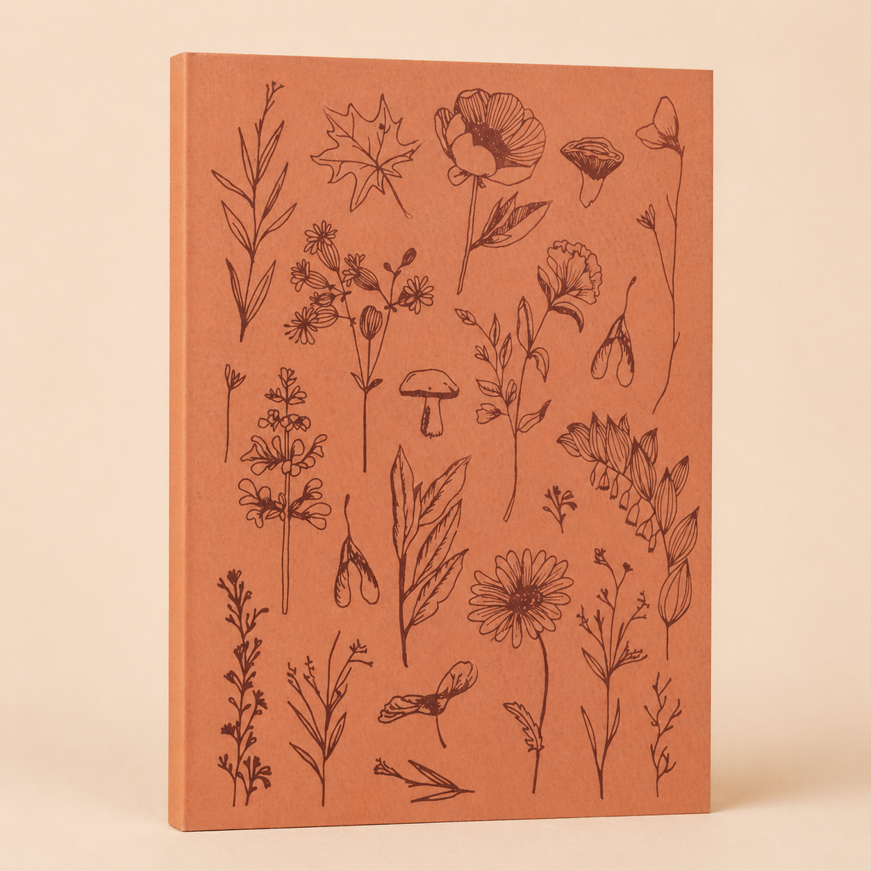 A closed orange notebook with black line drawings of various flowers, leaves, and mushrooms on its cover.