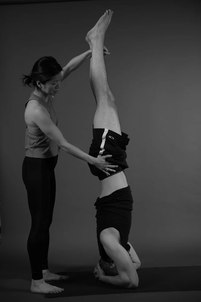 Mimi helping a friend with a shirshasana headstand