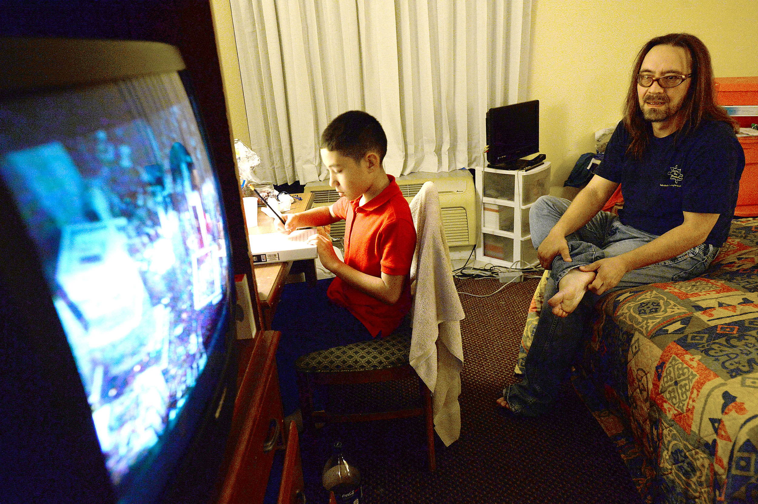 Steven Kaufman watches television while his son Stevie does homework at their hotel room in the Beaumont Lodge. The family have been staying there on a FEMA voucher after evacuating their flooded home 3 weeks ago.
Photo taken Wednesday, September 27