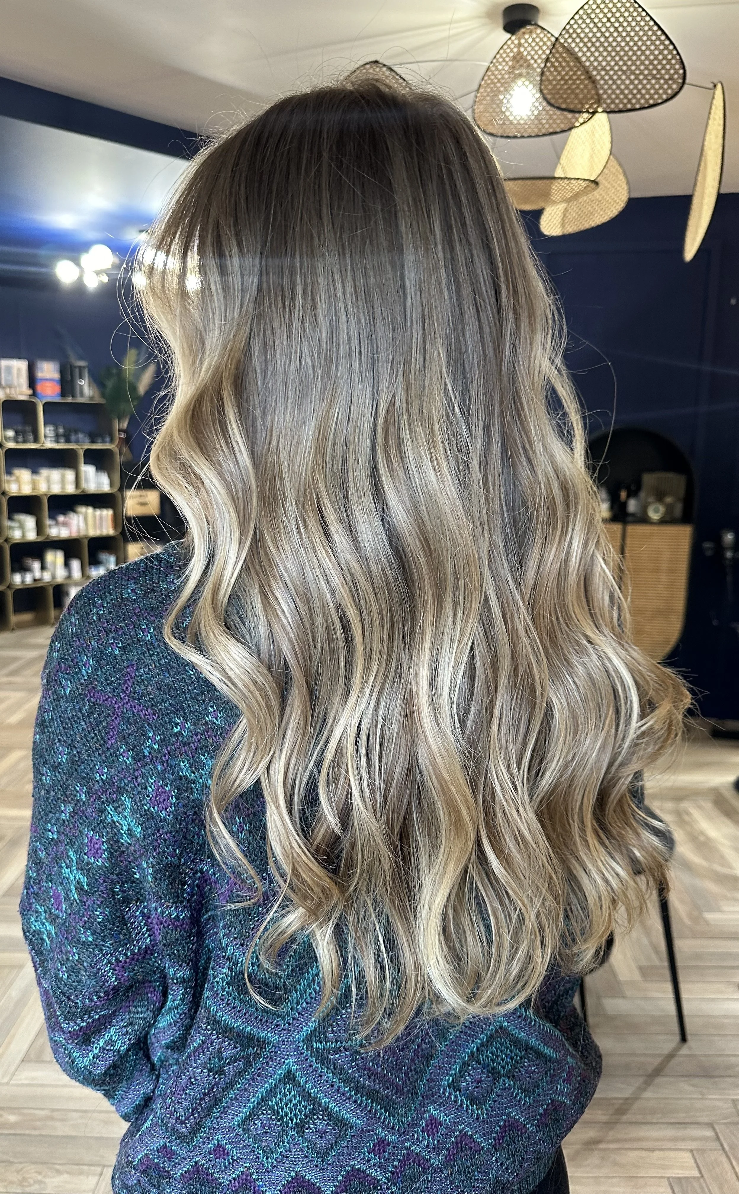 Cheveux longs et bouclés de couleur blonde avec des reflets